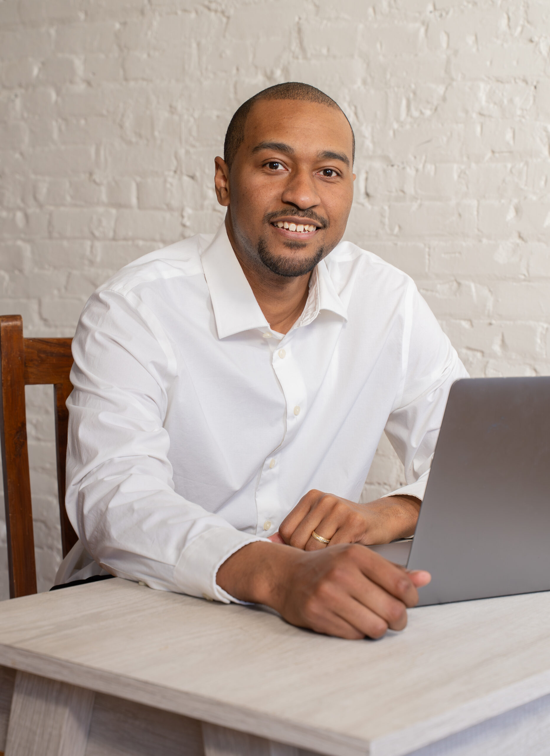 A picture of me (DaKarai Davison) sitting at a desk with a laptop smiling.